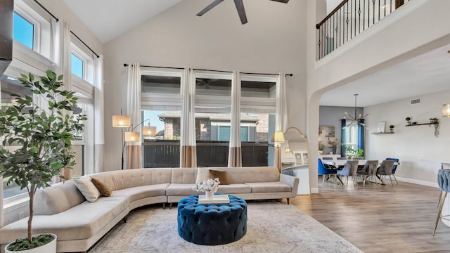 living room featuring a high ceiling, wood finished floors, visible vents, and baseboards