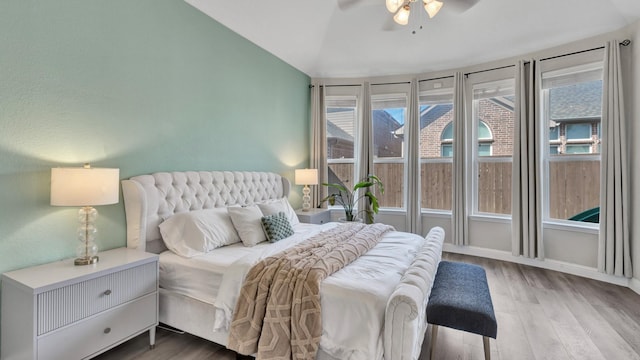 bedroom with ceiling fan, vaulted ceiling, baseboards, and wood finished floors