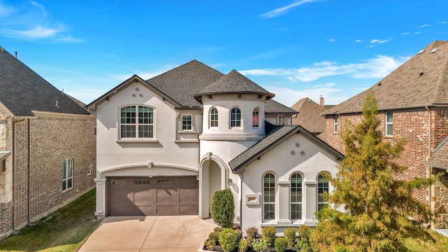 french country home featuring driveway, roof with shingles, a garage, and stucco siding