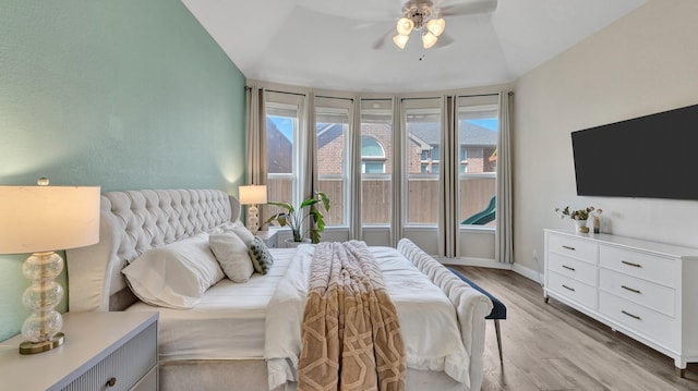 bedroom featuring multiple windows, vaulted ceiling, light wood-style flooring, and baseboards