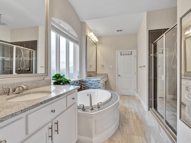 full bathroom with a stall shower, visible vents, a sink, a garden tub, and two vanities