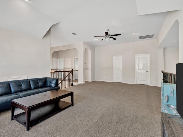 carpeted living area featuring arched walkways, baseboards, visible vents, and a ceiling fan