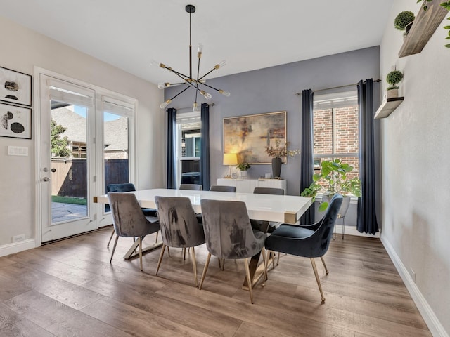 dining area featuring baseboards, an inviting chandelier, and wood finished floors