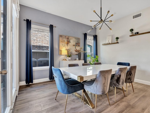 dining area with light wood-style floors, visible vents, and a healthy amount of sunlight