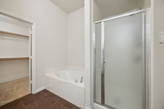 full bathroom with a stall shower, a walk in closet, a bath, and tile patterned floors