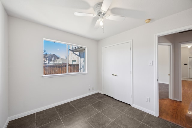 unfurnished bedroom with dark tile patterned floors, visible vents, a ceiling fan, baseboards, and a closet