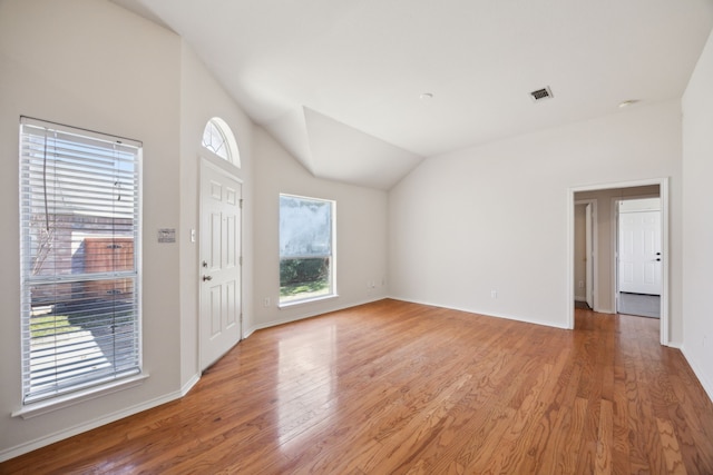 foyer entrance featuring light wood-type flooring, baseboards, visible vents, and lofted ceiling