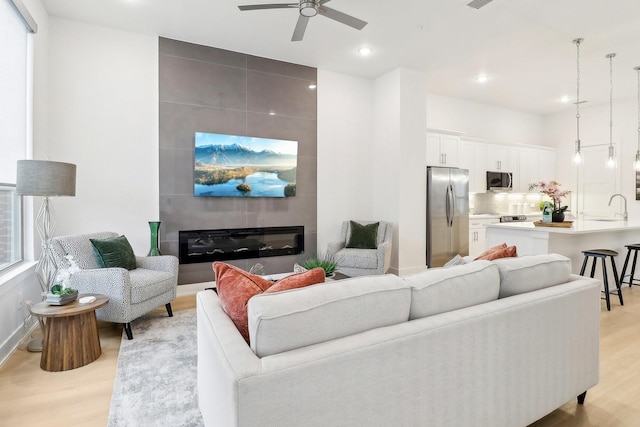 living area featuring ceiling fan, recessed lighting, a large fireplace, visible vents, and light wood-type flooring