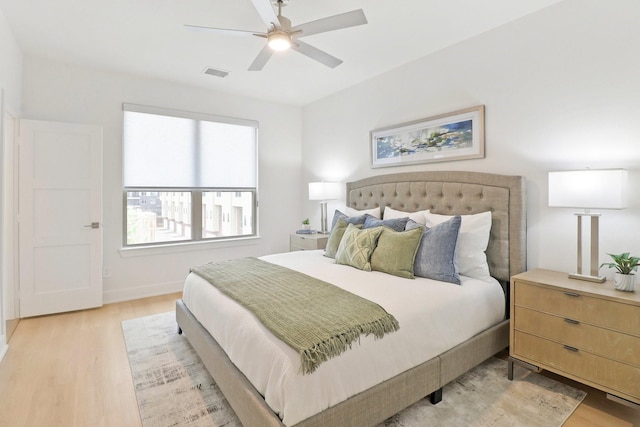 bedroom with light wood finished floors, ceiling fan, visible vents, and baseboards