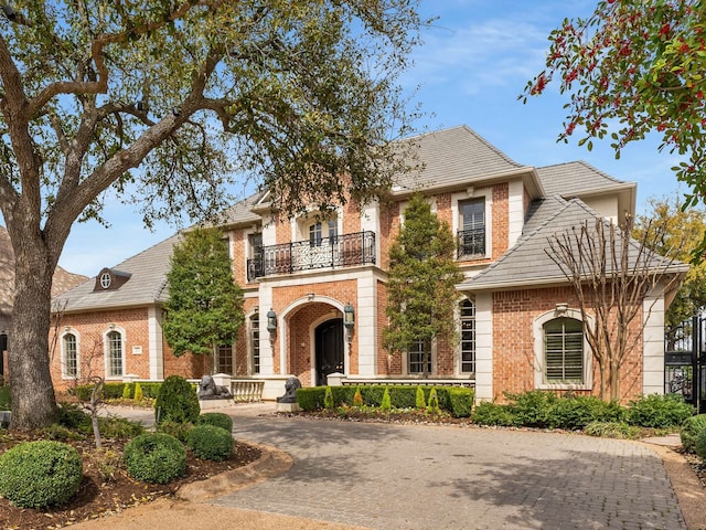 view of front of house with brick siding, driveway, and a balcony