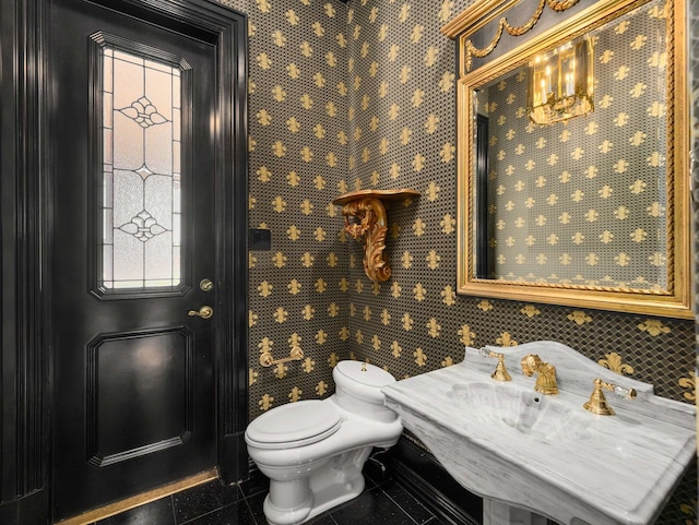 bathroom with tile patterned floors, a notable chandelier, toilet, and a sink