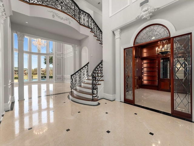 entryway with a chandelier, baseboards, a high ceiling, and ornate columns