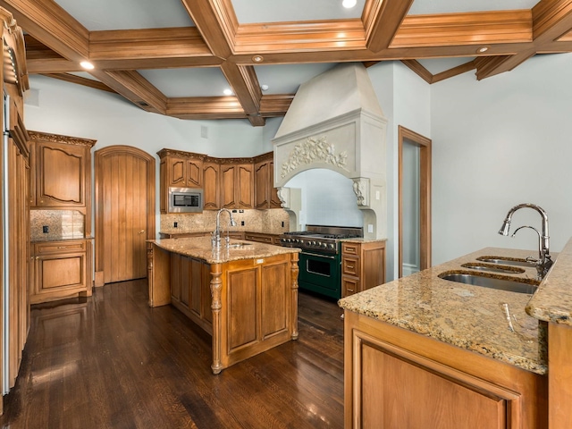 kitchen with stainless steel microwave, a center island with sink, double oven range, and a sink