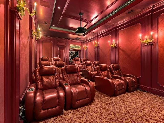 carpeted home theater room with a decorative wall, visible vents, and ornamental molding