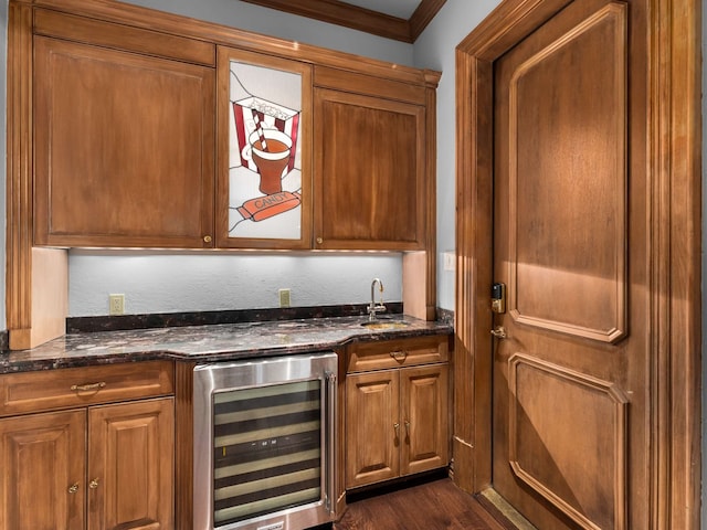 bar with beverage cooler, a sink, crown molding, wet bar, and dark wood-style flooring