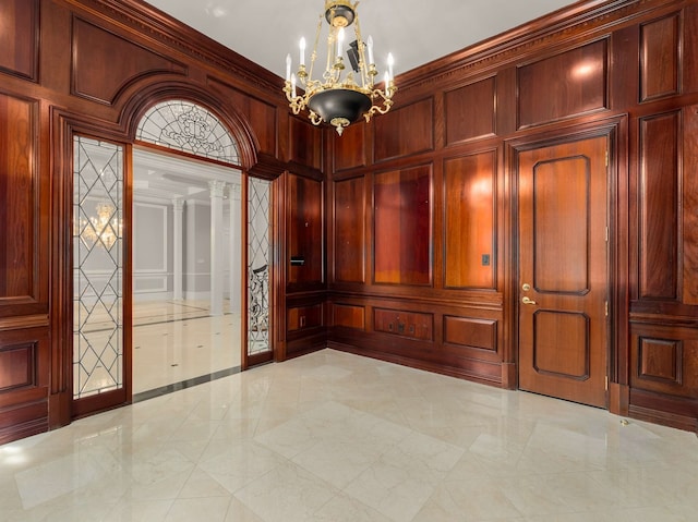 unfurnished room featuring crown molding, a decorative wall, wooden walls, and a chandelier