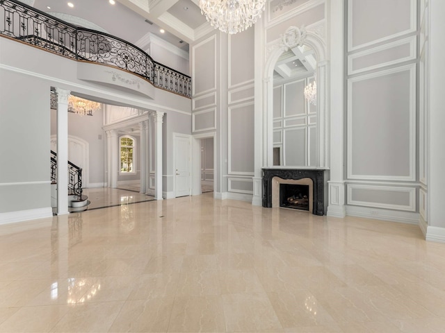 unfurnished living room with a decorative wall, coffered ceiling, a high ceiling, and an inviting chandelier