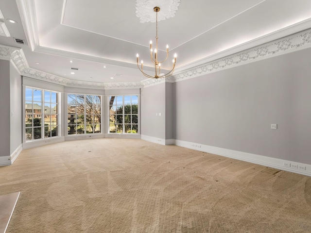 spare room with a tray ceiling, light carpet, an inviting chandelier, and visible vents