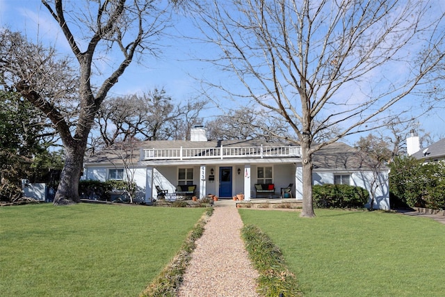 view of front of property with a chimney, a porch, and a front yard