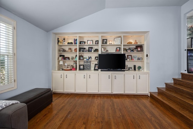 living room featuring dark wood-style flooring, vaulted ceiling, and stairway