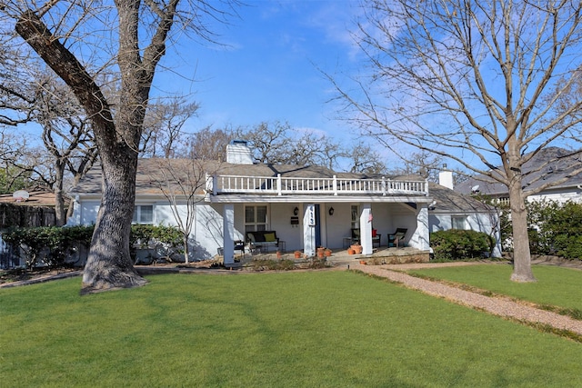 view of front of property with a porch, fence, a chimney, and a front lawn