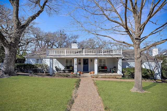 view of front of property with covered porch, a chimney, and a front lawn