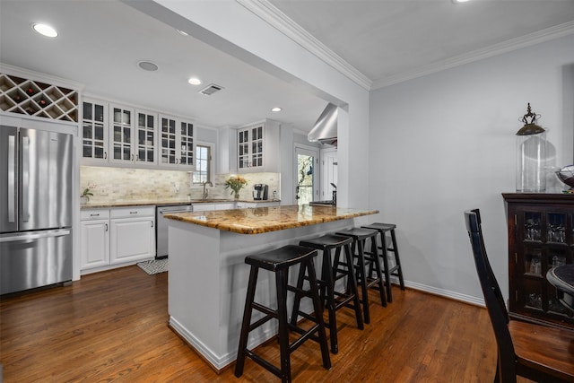 kitchen with light stone counters, stainless steel appliances, backsplash, dark wood-style floors, and crown molding