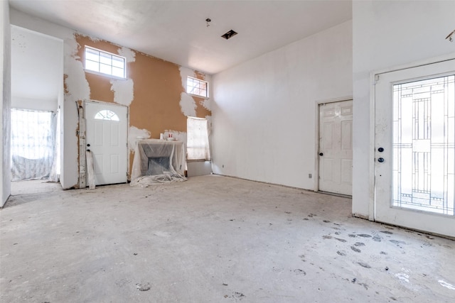 foyer featuring concrete floors and a towering ceiling