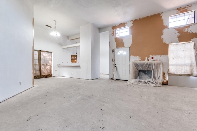 unfurnished living room with visible vents, concrete floors, a notable chandelier, and a high ceiling