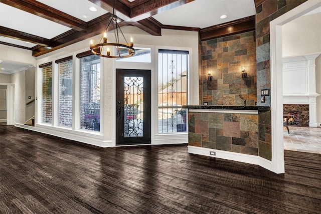 foyer with crown molding, a notable chandelier, a warm lit fireplace, coffered ceiling, and beamed ceiling