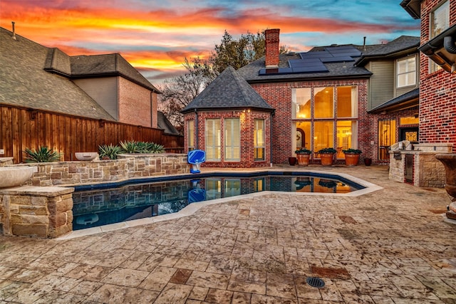 pool at dusk with a fenced in pool, an outdoor kitchen, a patio area, a grill, and fence