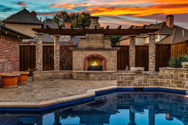 pool at dusk featuring fence and an outdoor stone fireplace