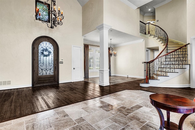 entrance foyer featuring a high ceiling, visible vents, baseboards, hardwood / wood-style floors, and ornate columns