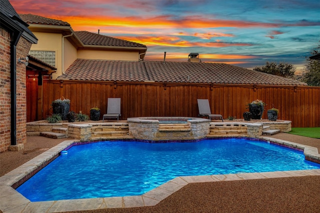 view of swimming pool with a fenced backyard and a pool with connected hot tub