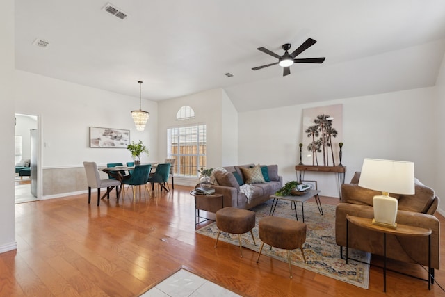 living room with visible vents, wood finished floors, and ceiling fan with notable chandelier