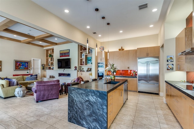 kitchen featuring a sink, open floor plan, appliances with stainless steel finishes, wall chimney exhaust hood, and dark countertops