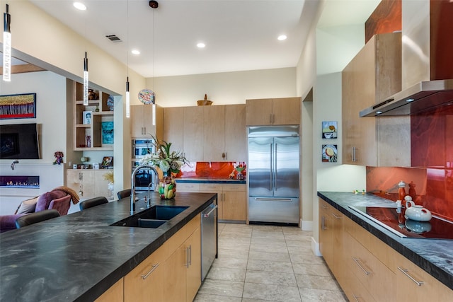 kitchen with stainless steel appliances, a sink, visible vents, wall chimney range hood, and pendant lighting