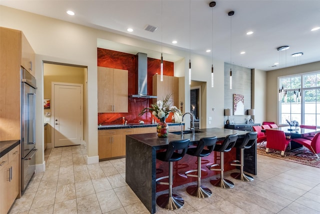 kitchen with wall chimney exhaust hood, a breakfast bar, dark countertops, and modern cabinets