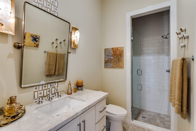 bathroom featuring toilet, a stall shower, and vanity