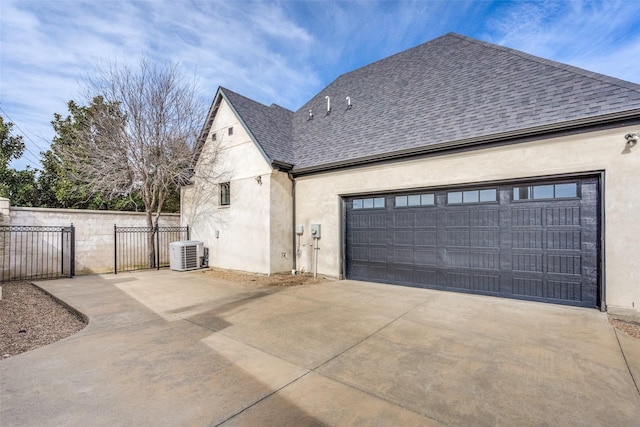 view of home's exterior with roof with shingles, stucco siding, concrete driveway, central AC unit, and fence