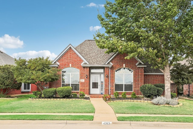 traditional-style house featuring brick siding, roof with shingles, and a front yard