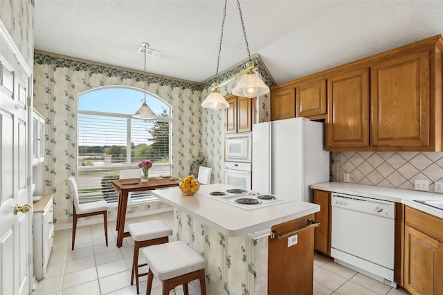 kitchen with a center island, brown cabinets, light countertops, white appliances, and wallpapered walls