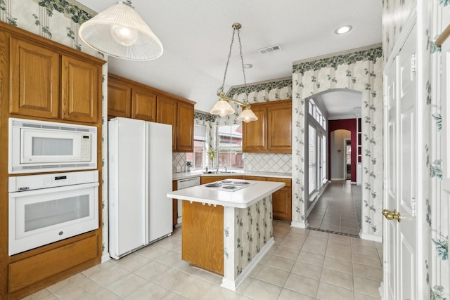 kitchen with arched walkways, white appliances, visible vents, and wallpapered walls