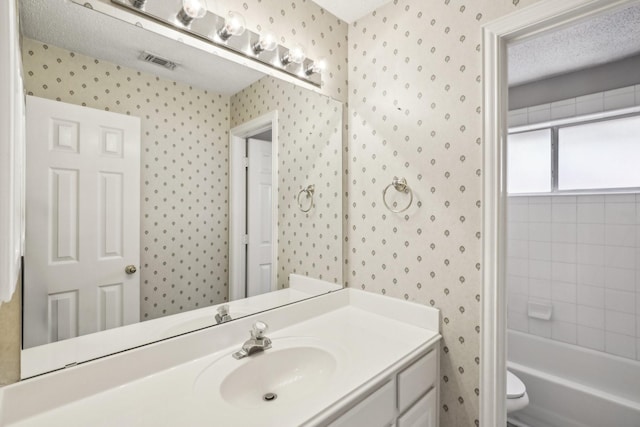 bathroom featuring toilet, vanity, visible vents, and wallpapered walls