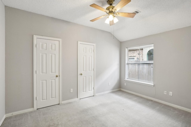 unfurnished bedroom with lofted ceiling, carpet flooring, a textured ceiling, and baseboards