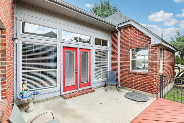 property entrance with brick siding, a patio area, and fence