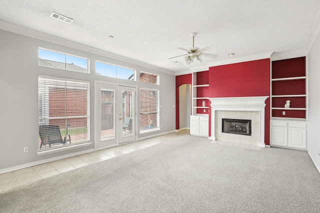 unfurnished living room with a textured ceiling, carpet floors, visible vents, built in features, and ornamental molding