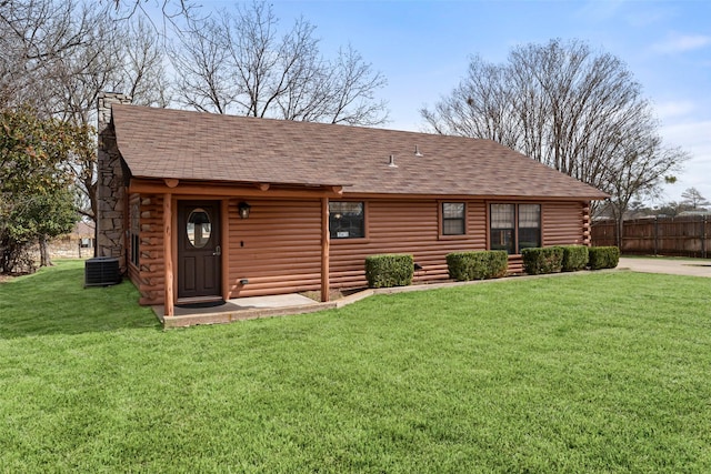 rear view of property featuring a yard, roof with shingles, cooling unit, and fence