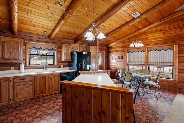 kitchen with wooden walls, a kitchen island, black appliances, a chandelier, and a sink