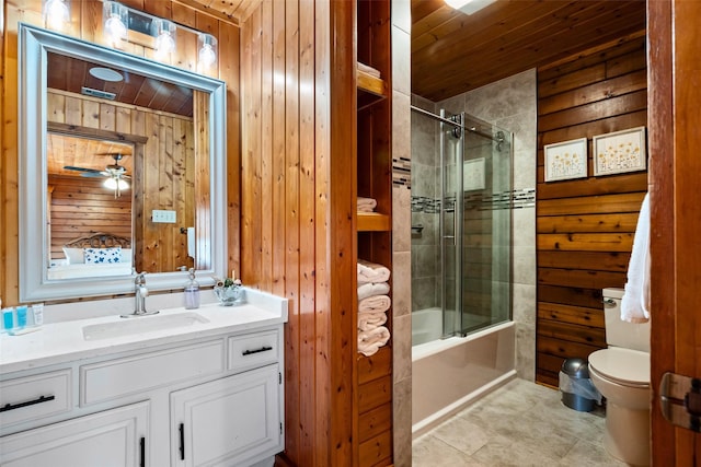 bathroom featuring toilet, a ceiling fan, combined bath / shower with glass door, wood walls, and vanity